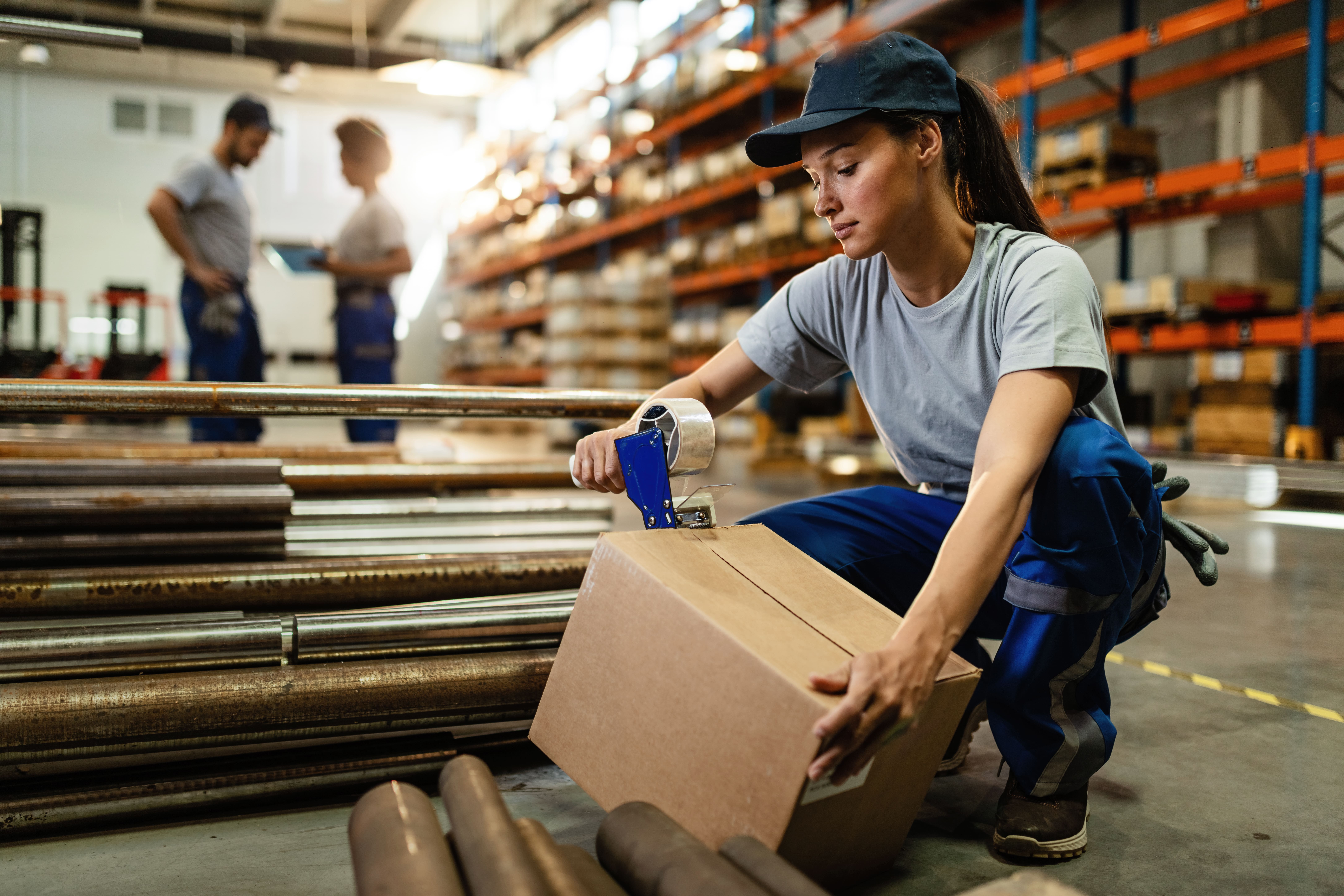 Female Warehouse Worker Taping Cardboard Box With Tape Dispenser Before Shipment 2